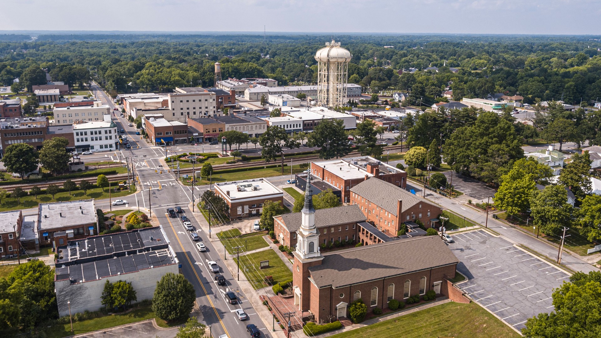 Summer day in Thomasville, NC. Cityscape with Church and Water Tower in the tree lined horizon. Downtown Cary Church in Public Buildings surroundings. Drone view