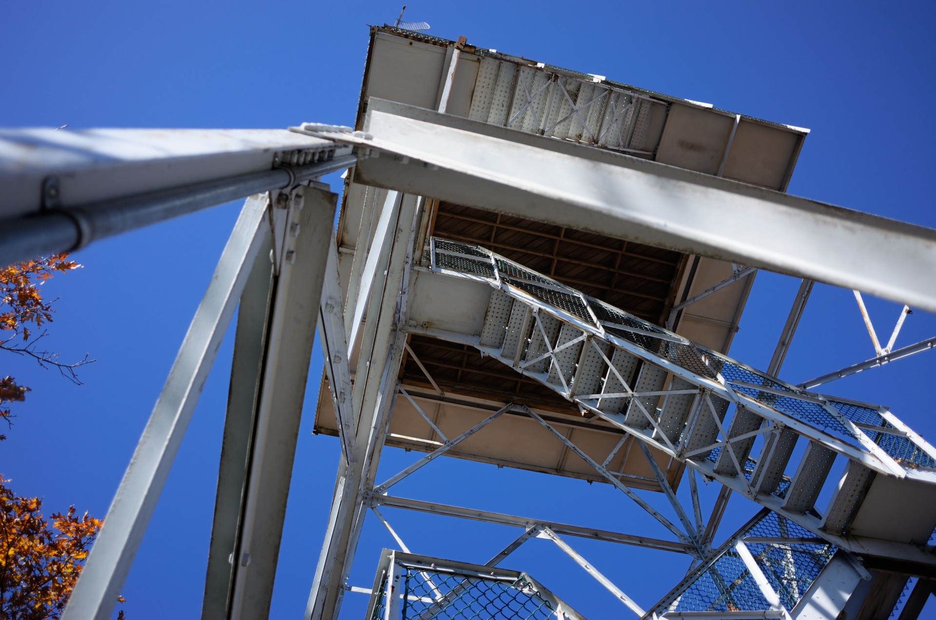 Looking up at metal fire tower against clear blue sky